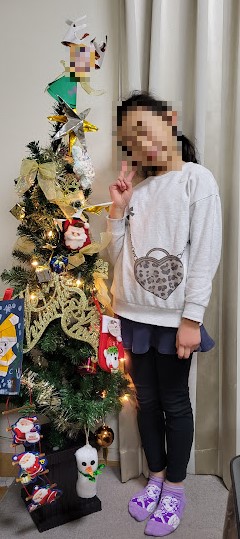 「クリスマスツリーと長女」うちのクリスマスツリーは学校や保育園で作ったものを追加するのでモリモリです。